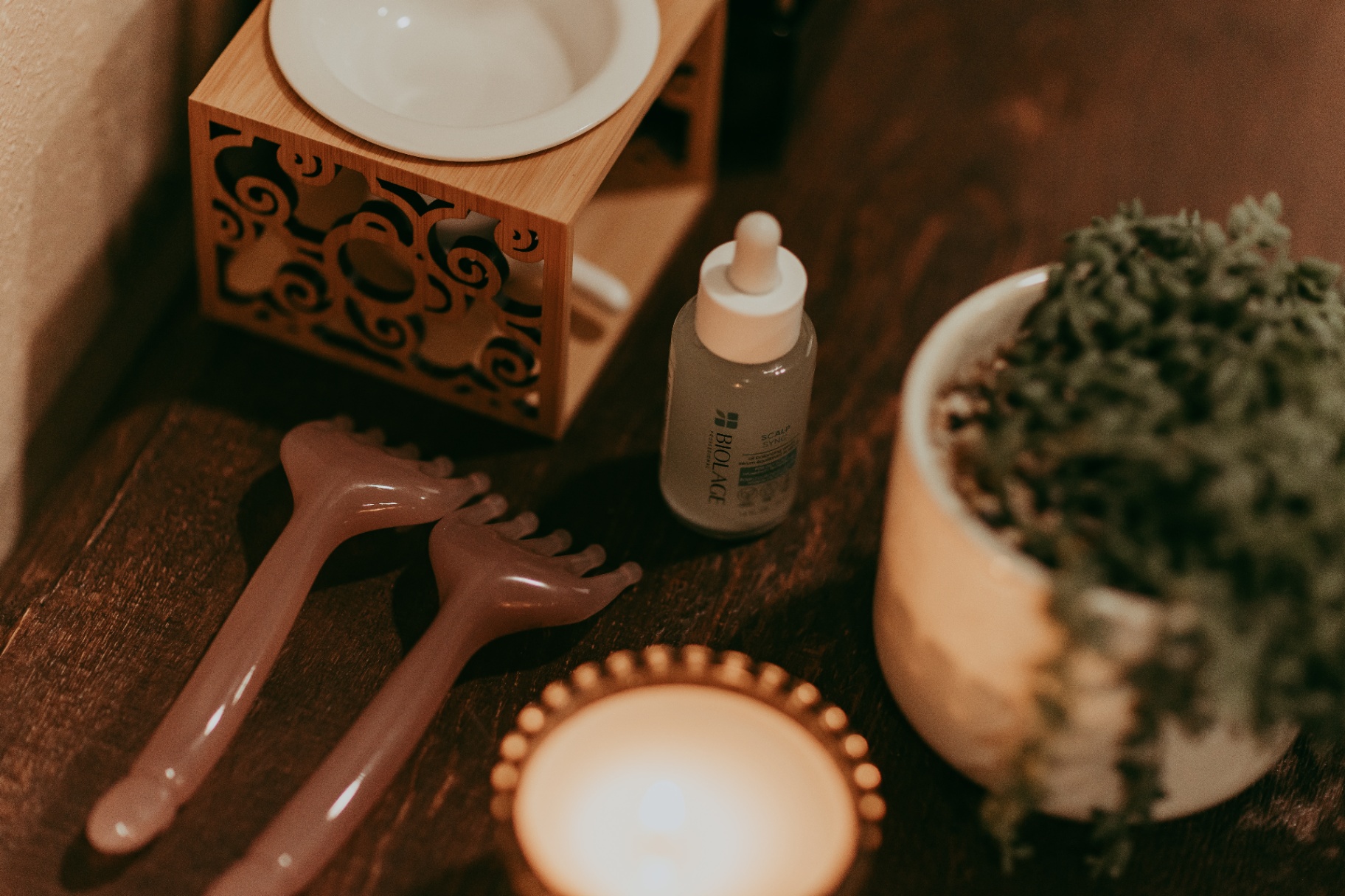 Head spa tools, candle and greenery flat lay
